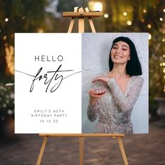 a woman holding a glass of wine in front of a sign that says hello party