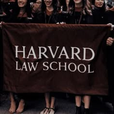 a group of women standing next to each other holding a harvard law school banner