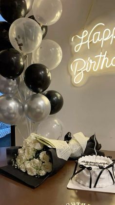 a birthday cake and some balloons on a table in front of a sign that says happy birthday