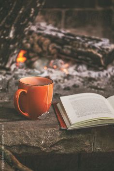 an open book sitting on top of a table next to a cup