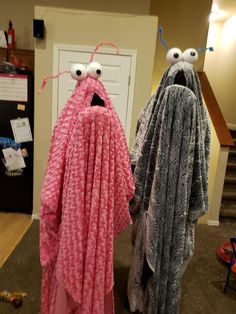 two towels that look like monsters standing next to each other in front of a door