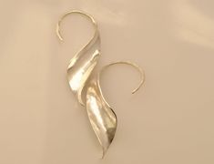 "I make these earrings from a sheet of sterling silver, using the hammering technique called anticlastic raising. This technique allows the earrings to be strong and light at the same time. These earrings are beautiful from any angle, and so can be worn in three different ways, equally striking: switching the one on the left ear with the one on the right gives you a different look, as does reversing the placement of the \"ear wire\" and earring body, so that the ear wire sits on the outside of t Luxury Sterling Silver Ear Wire Jewelry, Luxury Metal Earrings With Ear Wire, Luxury Hand Forged Earrings For Women, Fold Forming, Oxidized Silver Earrings, Ice Skater, Metalsmithing Jewelry, Silver Flower Earrings, Face Earrings