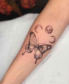 a butterfly tattoo on the arm with phases and stars around it, as well as planets