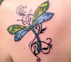 a colorful dragonfly tattoo on the back of a woman's shoulder