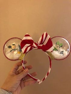 a hand holding up a minnie mouse headband with snowman and mickey mouse on it