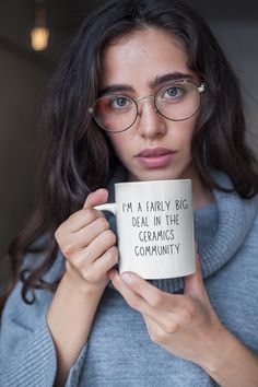 a woman wearing glasses holding a coffee mug