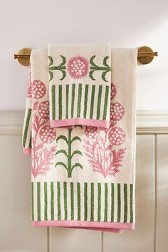 two towels hanging on the wall next to a towel rack with pink and green flowers