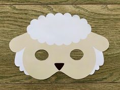 a paper sheep mask on a wooden surface