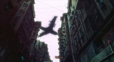 an airplane is flying through the sky between tall buildings