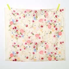 a white wall with a flowered cloth hanging from it's side and two yellow pegs