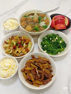 several bowls filled with different types of food on top of a white countertop next to an apple