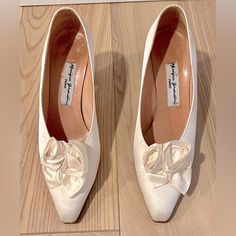 two pairs of white shoes with bows on the toes and heels are sitting on a wooden floor