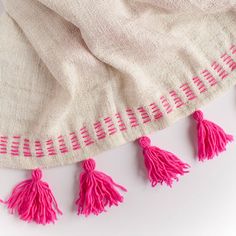 the pink tassels are hanging from the white blanket