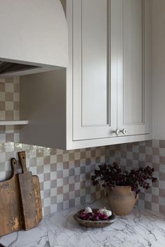 a kitchen with marble counter tops and white cupboards next to a wooden cutting board