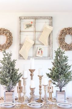 christmas decorations with stockings hanging on the wall and candles in front of them, along with two wreaths