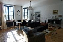 a living room filled with furniture and a chandelier hanging from the ceiling in front of two windows