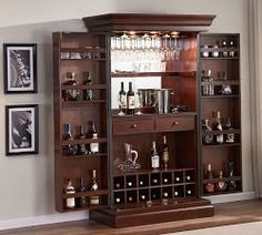 a wooden bar with wine glasses and liquor bottles on the shelves in front of it