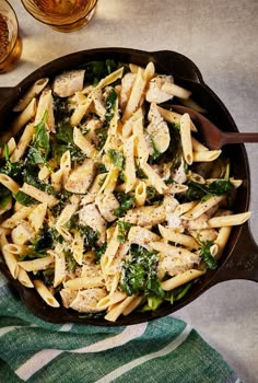 a skillet filled with pasta, chicken and spinach