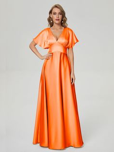 a woman in an orange dress poses with her hands on her hips and one hand on her hip