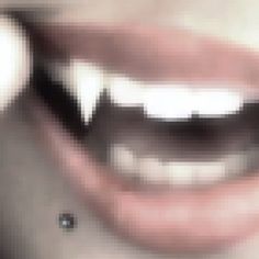 a close up of a person's mouth with white teeth and black eyeliners