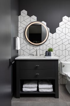 a black and white bathroom with hexagonal tiles on the wall, sink and toilet