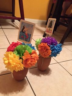 two vases filled with colorful flowers on top of a tiled floor