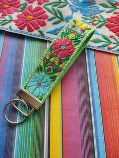 a keychain that is sitting on top of a colorful striped cloth with flowers