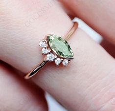 a woman's hand with a ring on it and an oval shaped green stone in the middle