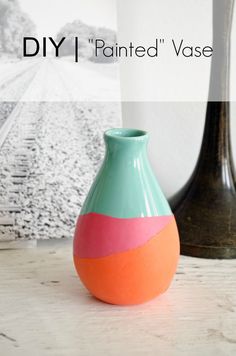 a vase sitting on top of a wooden table next to a black and white vase