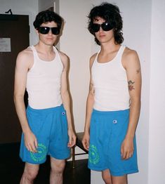 two young men standing next to each other in front of a mirror with sunglasses on