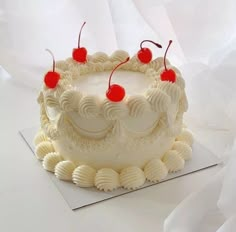 a white frosted cake with cherries on top