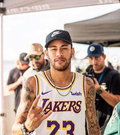 a man with tattoos on his arm and wearing a lakers jersey pointing to the side