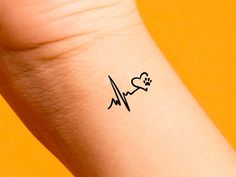 a small heart and heartbeat tattoo on the left arm with a dog's paw