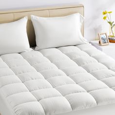 a white bed with two pillows on top of it