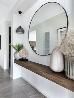 there is a mirror and vases on the shelf in this room with tile flooring