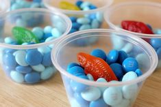 four plastic cups filled with candy candies on top of a wooden table