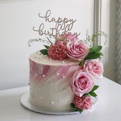 a birthday cake decorated with pink flowers and the words happy birthday written on top in cursive writing