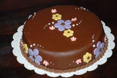 a chocolate cake decorated with flowers on a doily