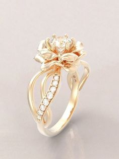 a gold ring with a flower on it's side and diamonds in the middle