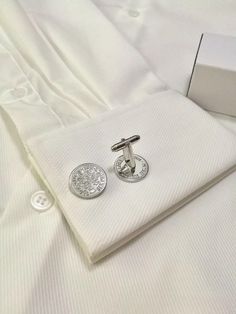 These cufflinks are crafted from silver sixpence coins, a traditional British coin often associated with good luck, particularly in weddings. The sixpence cufflinks showcase intricate floral designs from the original coin, adding a vintage charm to formal wear. These handmade accessories would be perfect for wedding attire, offering a touch of classic elegance with a meaningful symbol. Wedding Shirt, Wedding Silver, Wedding Shirts, Cufflinks Wedding, Silver Cufflinks, Tie Accessories, Cuff Links, Silver Wedding, Wedding Attire