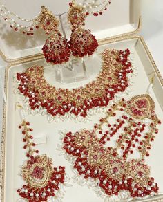 a white box with red and gold jewelry in it's display case on top of a table