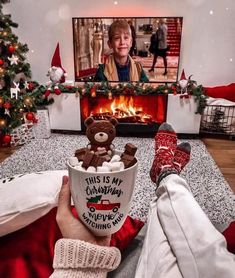 a person holding a cup with marshmallows in front of a fireplace