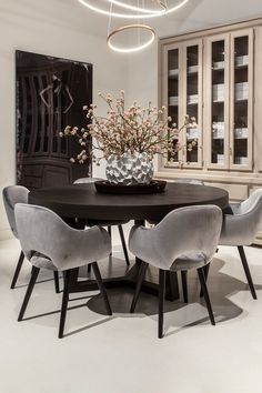 a dining room table with chairs and a vase filled with flowers