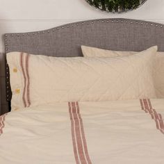 a bed with white sheets and red striped bedspread in front of a round mirror on the wall