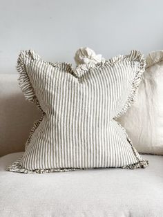 a striped pillow with ruffled edges on a white couch