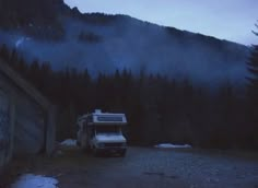 a white truck parked in front of a mountain with trees on it's side