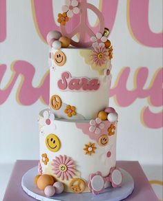 a three tiered cake decorated with flowers and peace signs