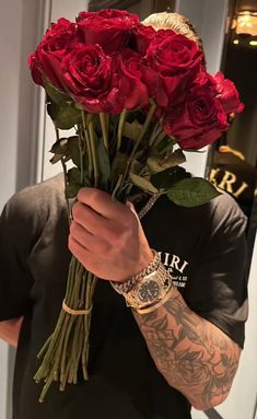 a man holding a bunch of red roses in his right hand and wearing a watch on his left wrist