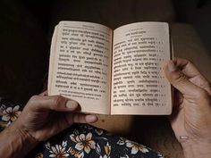 an old woman is reading a book in her lap and holding it up to the camera