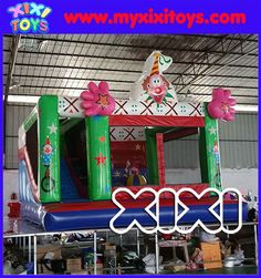 an inflatable bouncer with pink flowers on top and green poles, sitting inside a warehouse